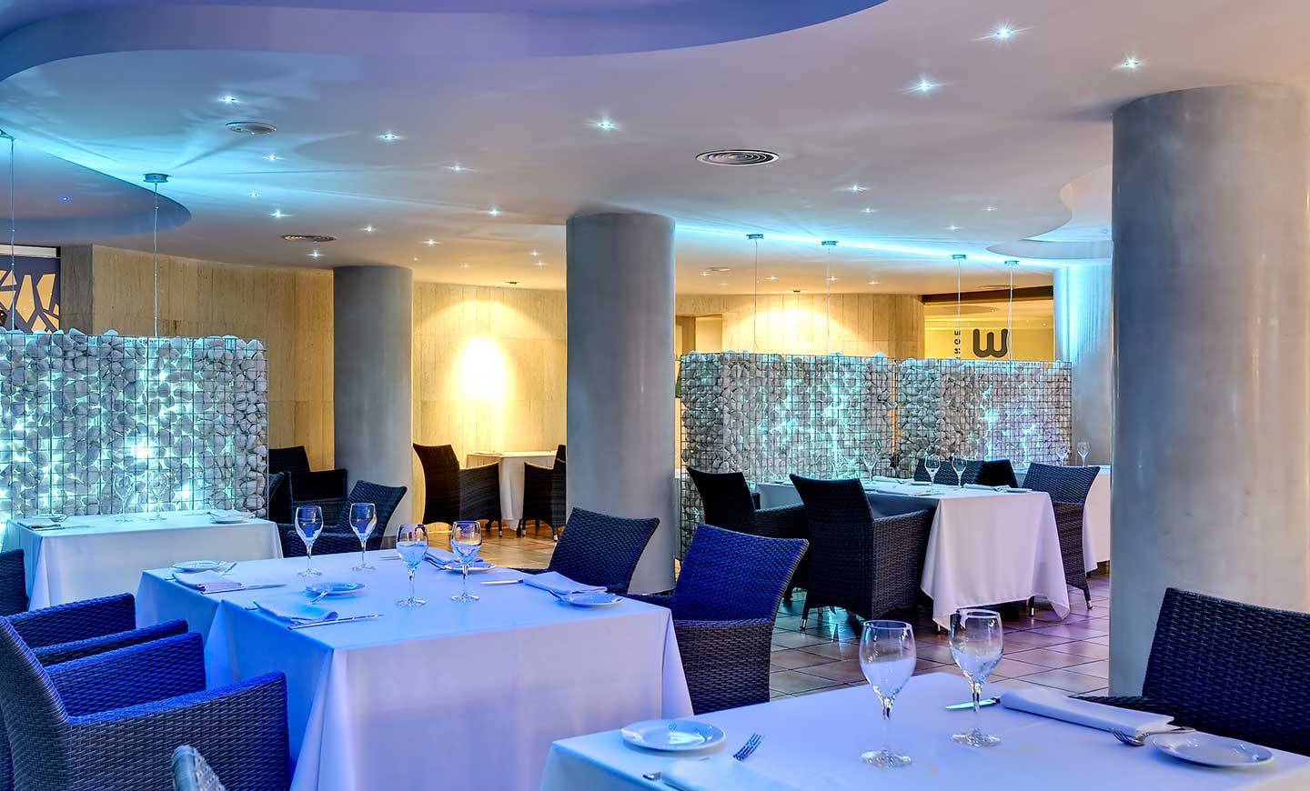 Innenansicht des Restaurants im Barcelo Illetas Albatros Hotel mit blauen Möbeln und weißen Tischen.