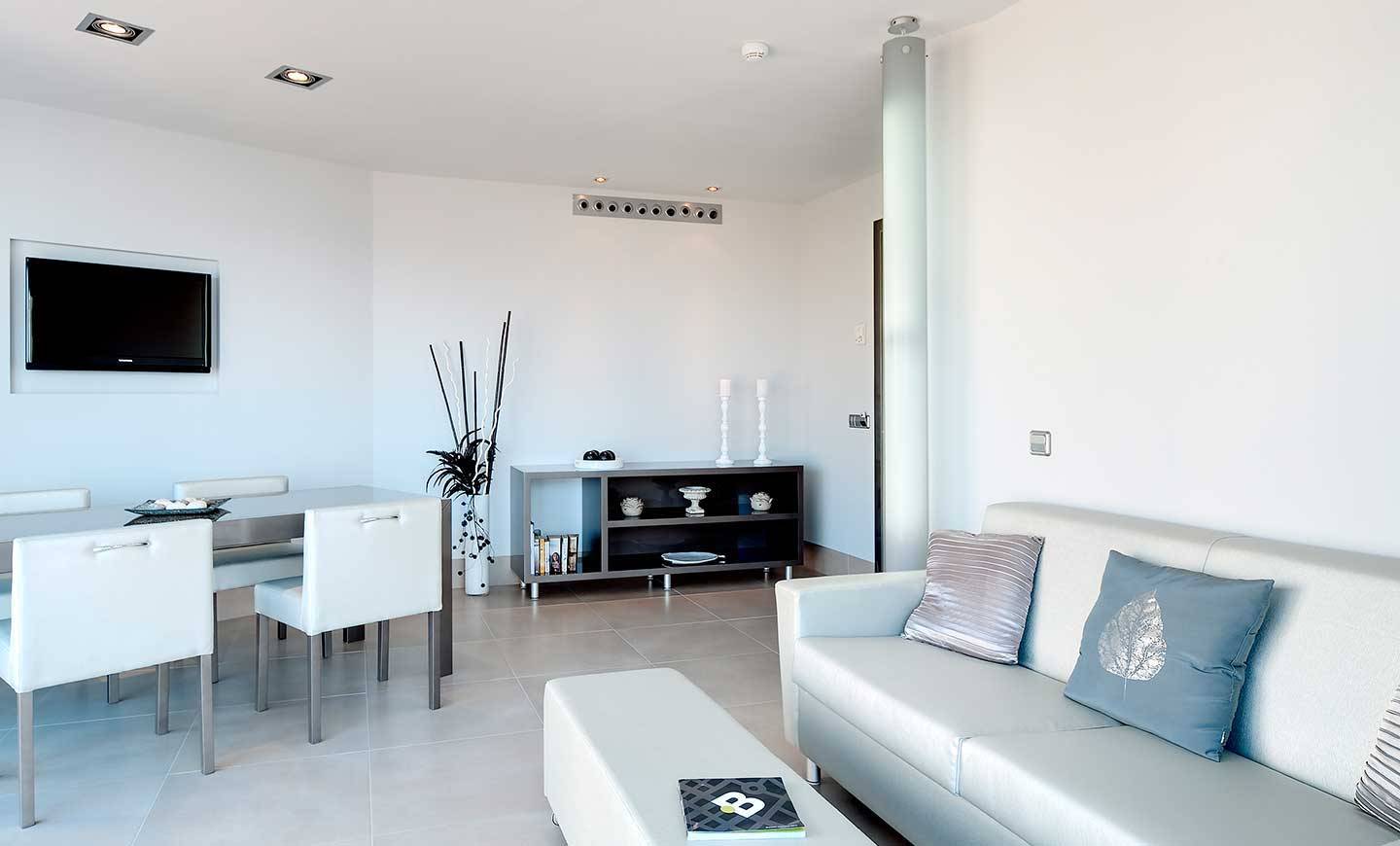 Wohnbereich des Barcelo Illetas Albatros Hotel mit weißem Esstisch, Stühlen und Sofa.