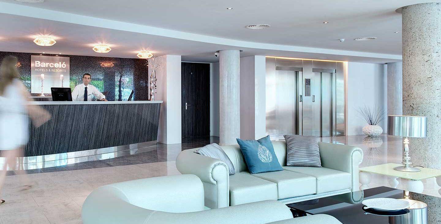 Empfangsbereich des Barcelo Illetas Albatros Hotel mit Rezeption, Sofas und Lampen.