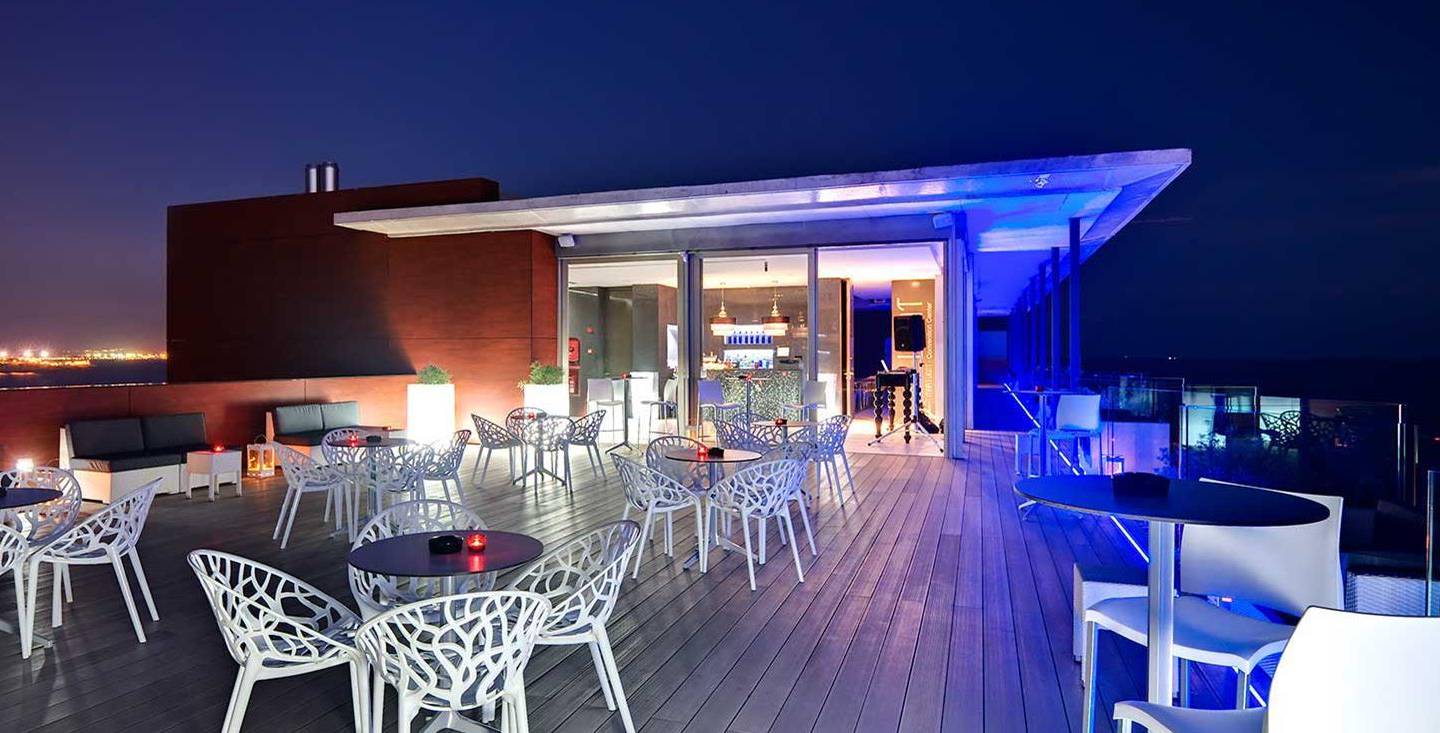 Außenterrasse des Barcelo Illetas Albatros Hotel bei Nacht mit beleuchteten Tischen und Stühlen.