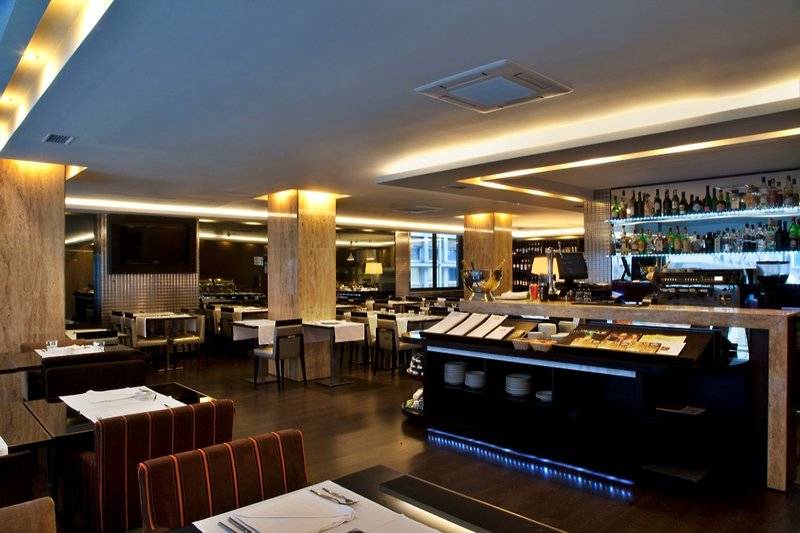 Innenraum des Turim AV Liberdade Hotels mit Tischen, Stühlen und einer Bar.