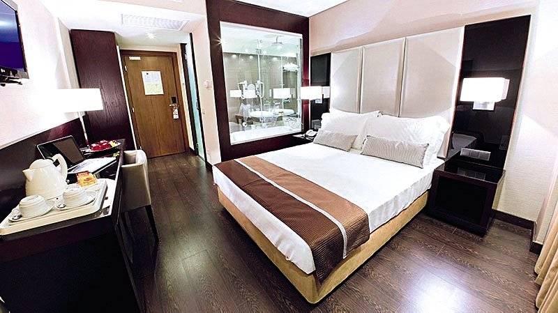 Ein modernes Hotelzimmer im Turim AV Liberdade Hotel mit einem Doppelbett, Schreibtisch, Laptop, und Badezimmerspiegel.