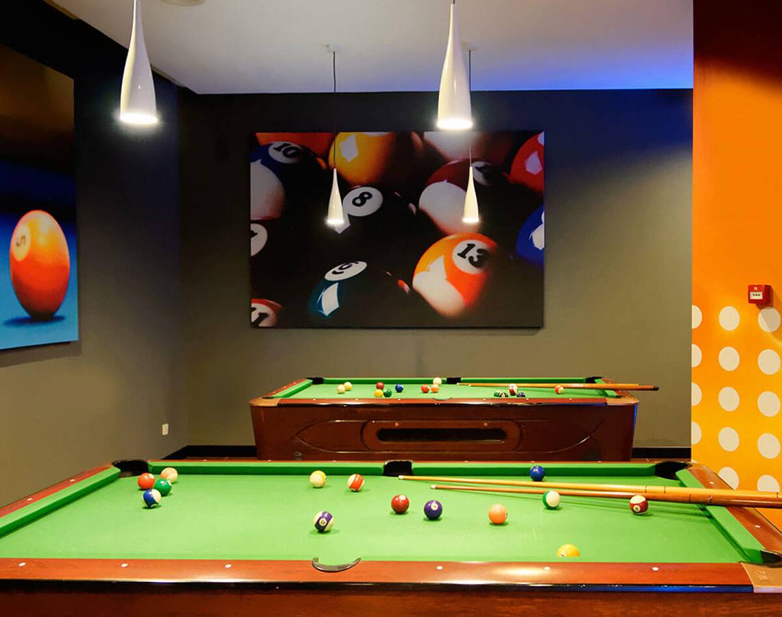 Billardraum im Servatur Waikiki Hotel mit zwei Billardtischen, einer an der Wand und vielen bunten Bällen.