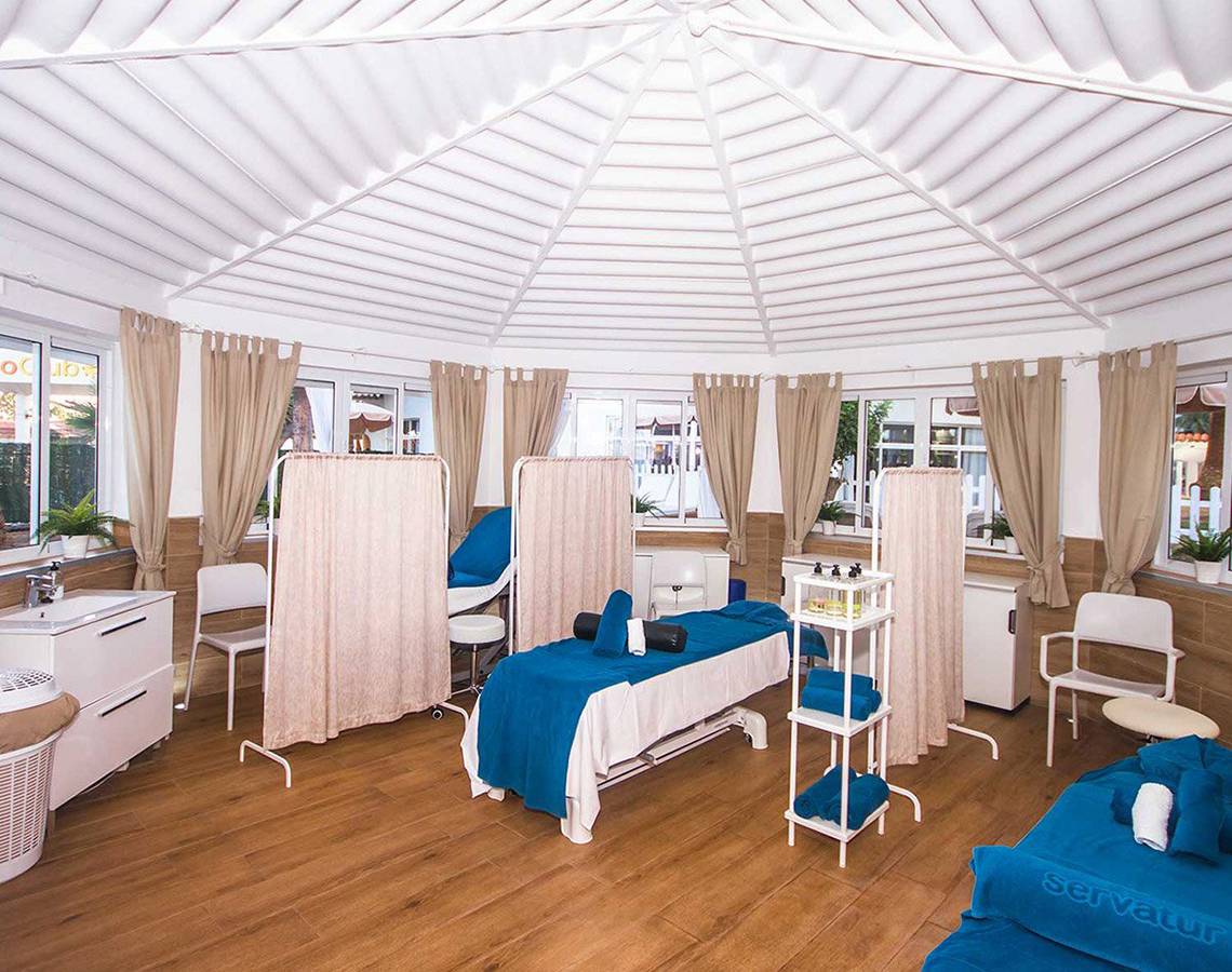 Behandlungsraum im Servatur Waikiki Hotel mit Massageliegen und blauen Laken.