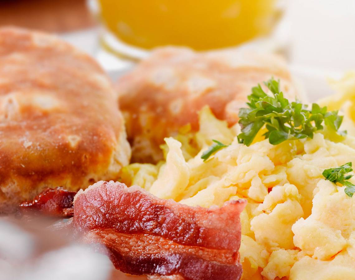 Frühstück mit Speck und Eiern, serviert auf einem weißen Teller.