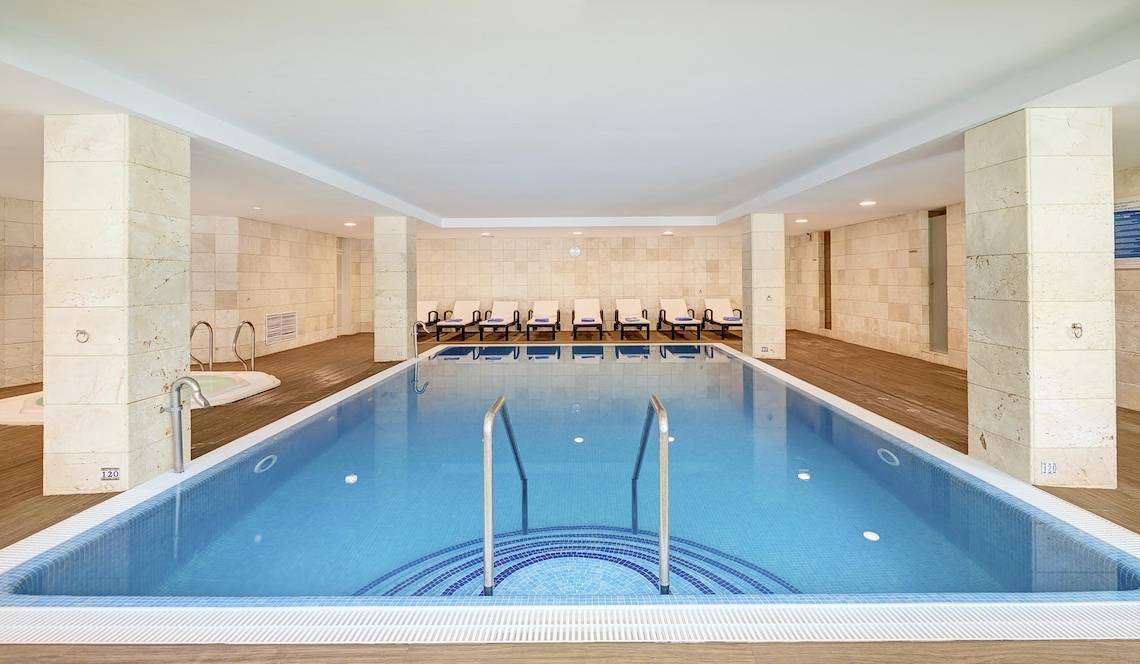 Schwimmbecken im Hipotels Hipocampo Playa Hotel mit weißen Wänden und Holzboden