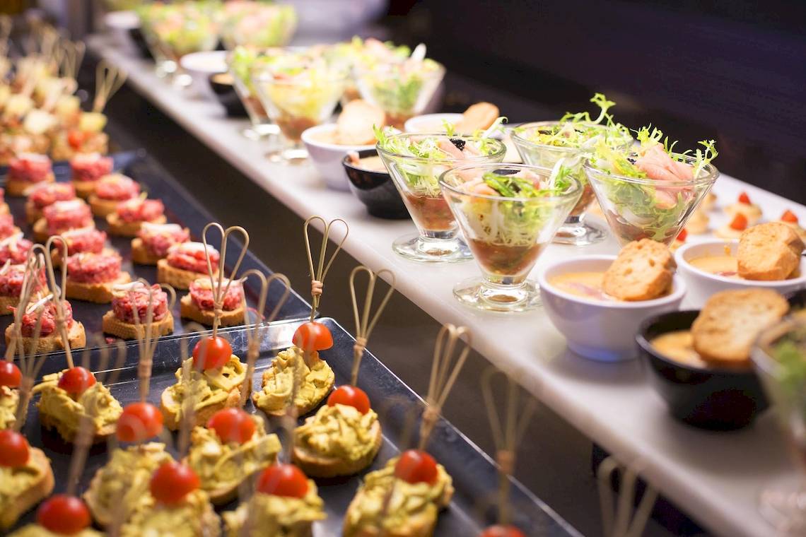 Buffet mit Happen und Salaten auf einer langen Tafel serviert