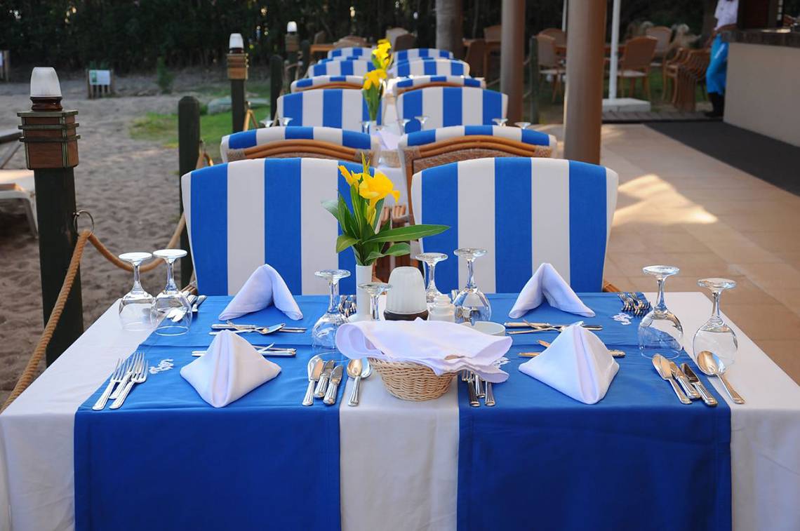 Fame Residence Lara & Spa Esstisch am Strand mit blau-weiß gestreiften Stühlen und Tischdecken.