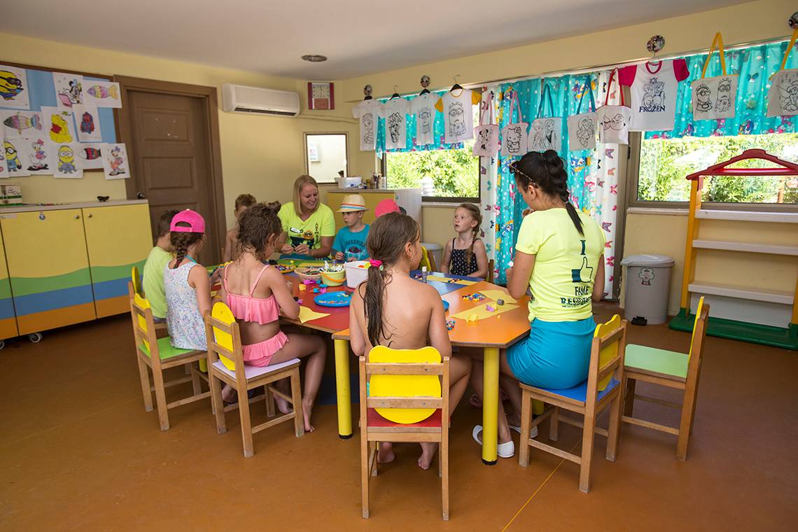 Kindergruppe im Fame Residence Lara & Spa, alle sitzen um einen Tisch herum und malen.