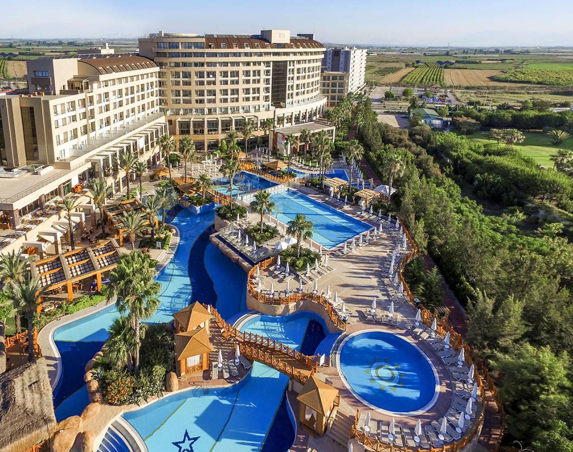 Luftaufnahme des Fame Residence Lara & Spa Hotels mit mehreren Swimmingpools und Sonnenliegen