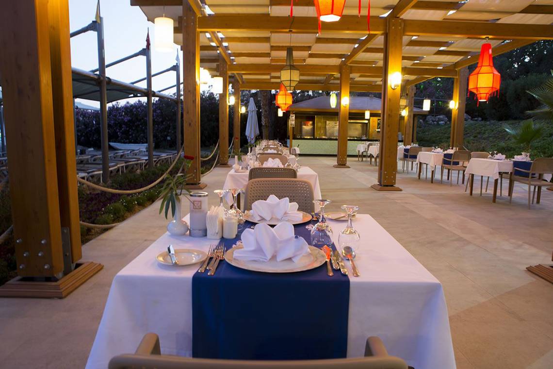 Fame Residence Lara & Spa Restaurant Innenraum mit gedeckten Tischen und dekorativen Lampen.