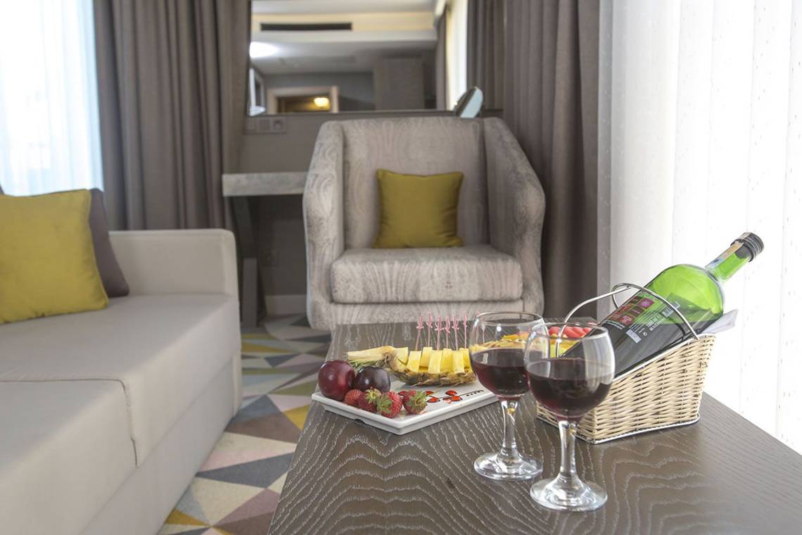 Wohnzimmer mit Tisch, Sofa und Stuhl im Fame Residence Lara & Spa Hotel.