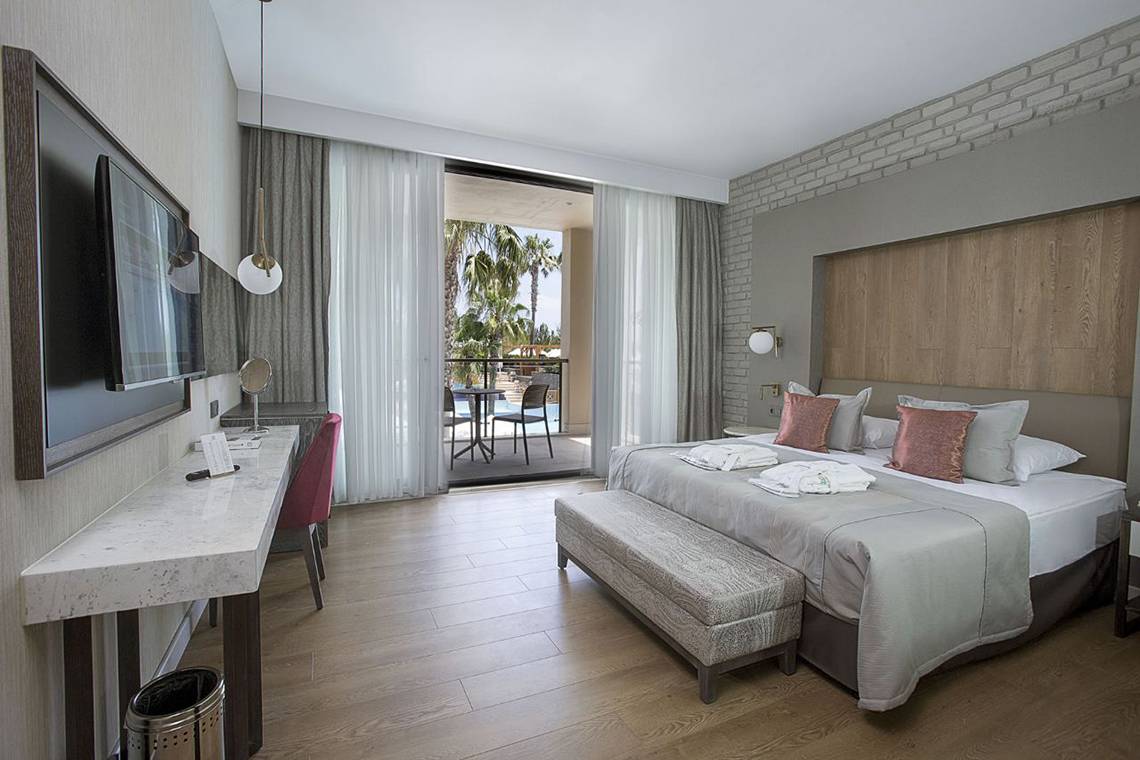 Hotelzimmer im Fame Residence Lara & Spa mit Doppelbett, Balkon und Ausblick auf einen Swimmingpool.