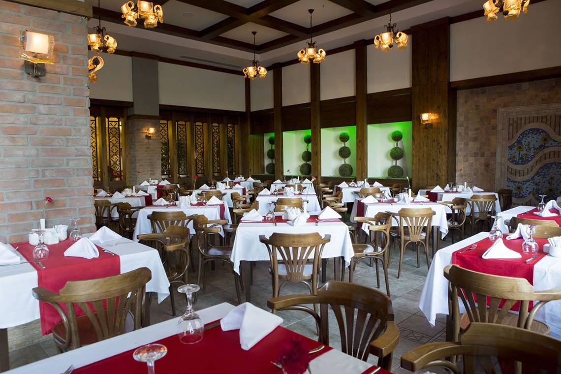 Innenansicht des Restaurants im Fame Residence Lara & Spa Hotel mit gedeckten Tischen und Stühlen.