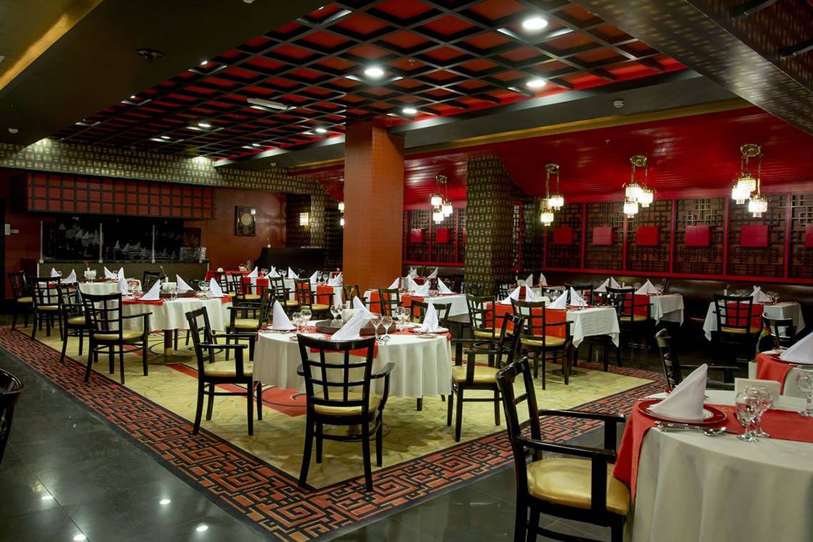 Innenansicht des Restaurants im Fame Residence Lara & Spa Hotel mit roten Wänden und Tischdecken.