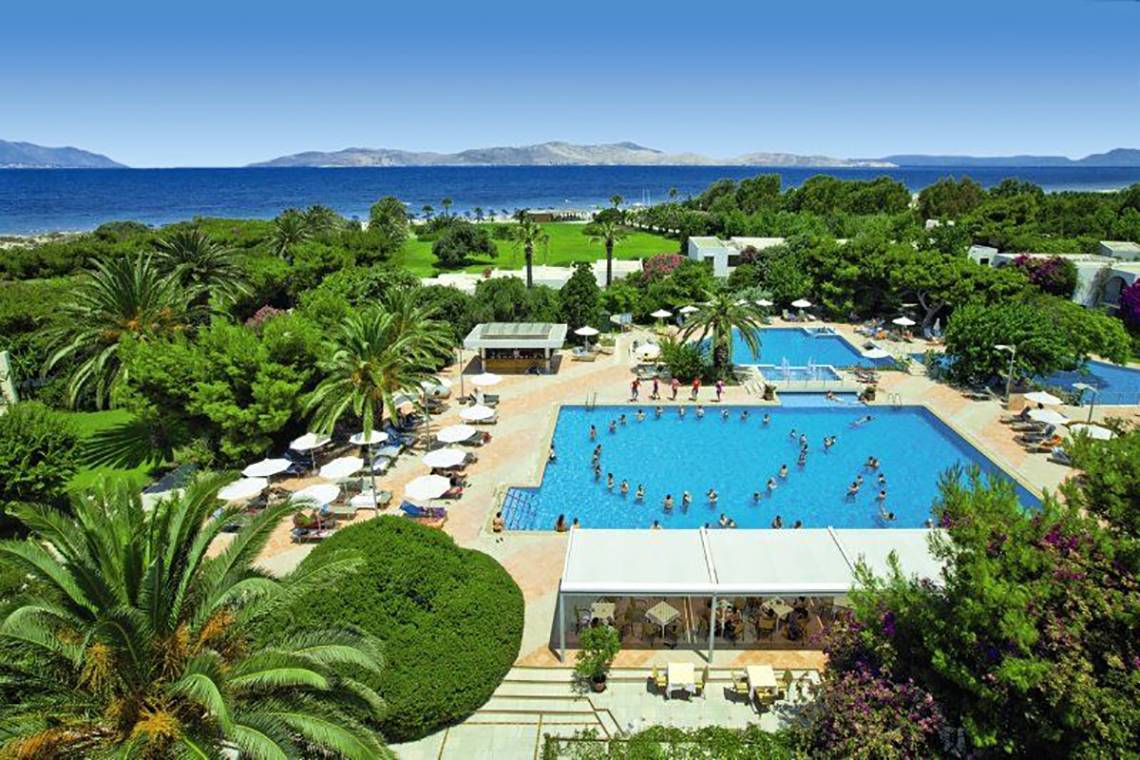 Luftaufnahme des Caravia Beach Hotel mit Swimmingpools, Palmen und Blick auf das Meer.