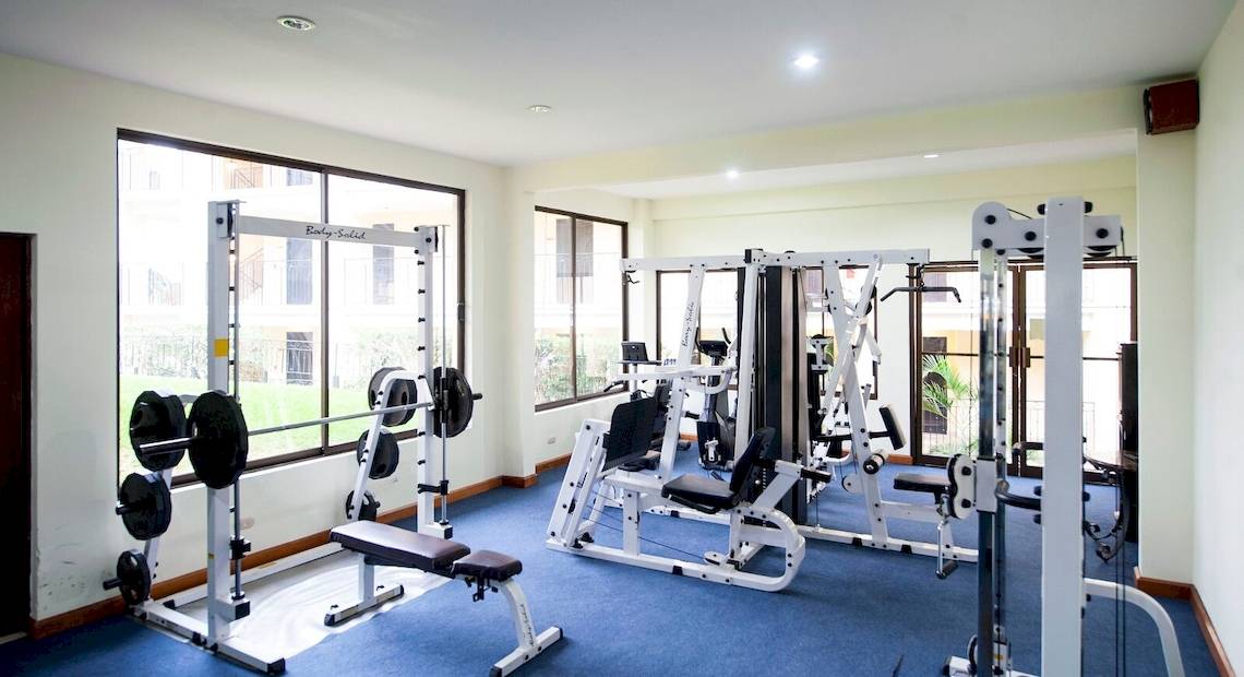 Fitnessraum im Occidental Papagayo Hotel mit verschiedenen Trainingsgeräten und großen Fenstern.