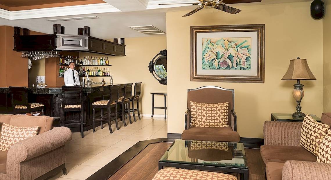 Der Barbereich des Occidental Papagayo Hotels mit einem Barkeeper und kunstvollen Wanddekorationen.