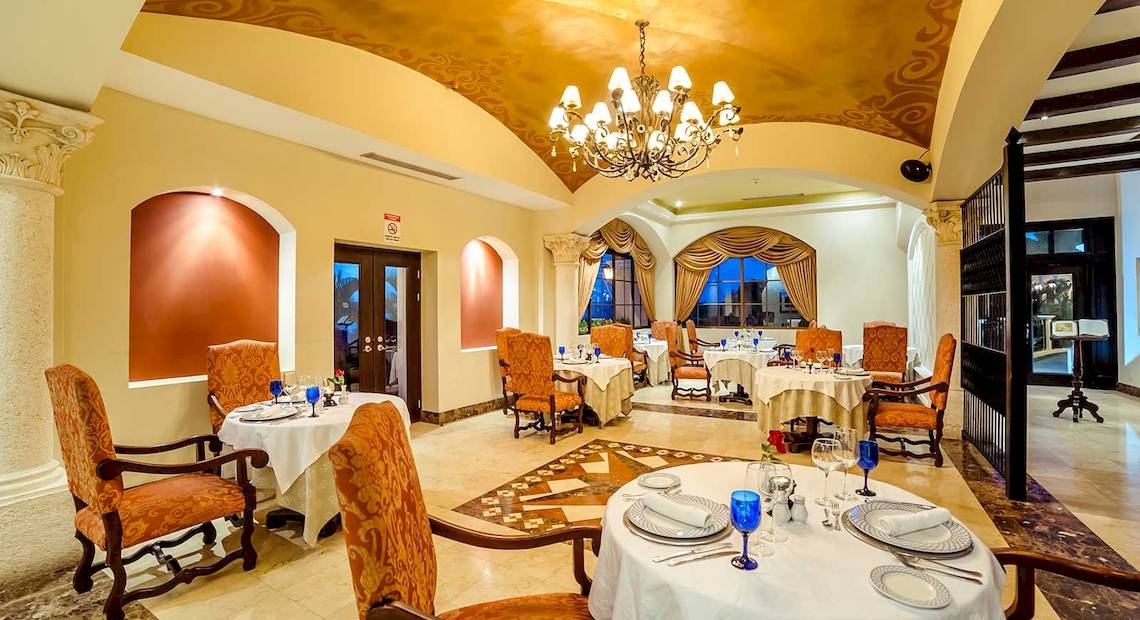 Innenansicht des Restaurants im Occidental Papagayo Hotel mit gedeckten Tischen und Stühlen, einer großen Deckenleuchte und großen Fenstern.