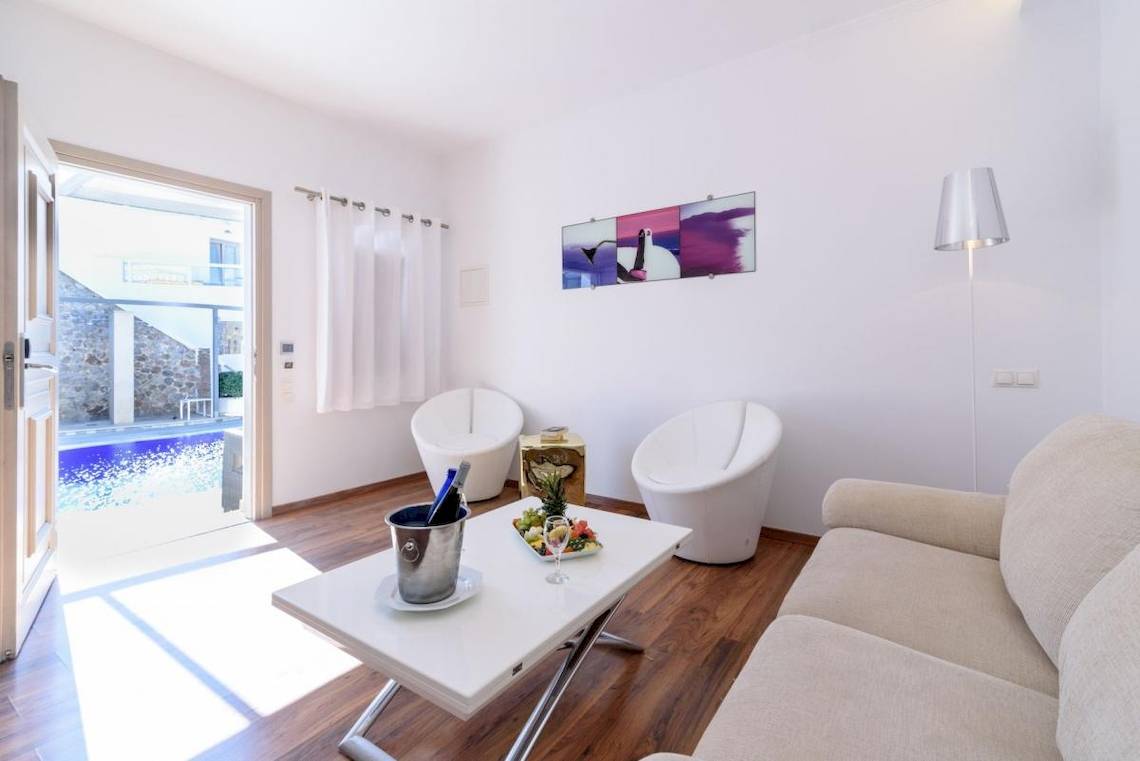 Wohnbereich des La Mer Deluxe Hotel & Spa mit Swimmingpool, weißer Einrichtung und Obstteller auf dem Tisch.