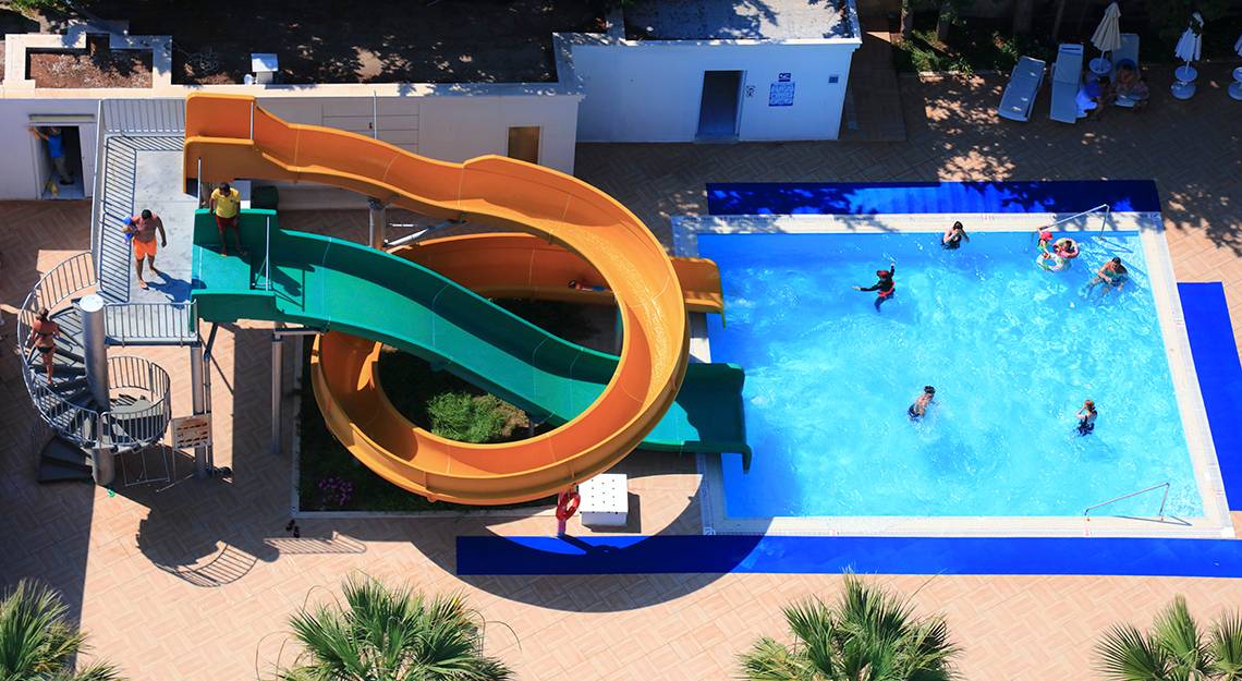 Foto des Schwimmbads im LABRANDA TMT Bodrum Hotel mit einer großen Wasserrutsche und mehreren Personen, die schwimmen.