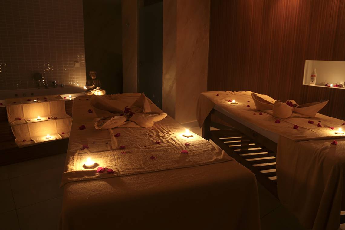 Spa-Behandlungsraum im Labranda TMT Bodrum mit zwei Massagetischen, dekoriert mit Kerzen und Rosenblättern.