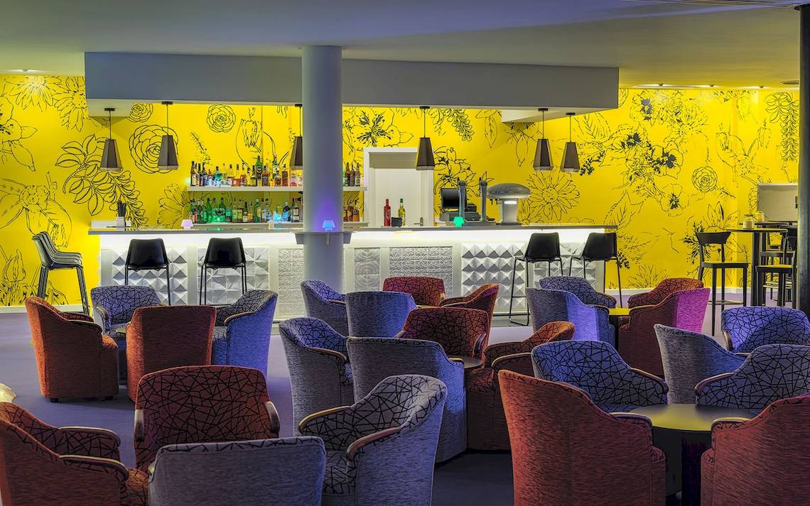 Lobby des H10 Suites Lanzarote Gardens Hotels mit gelben Wänden und vielen bunten Stühlen.