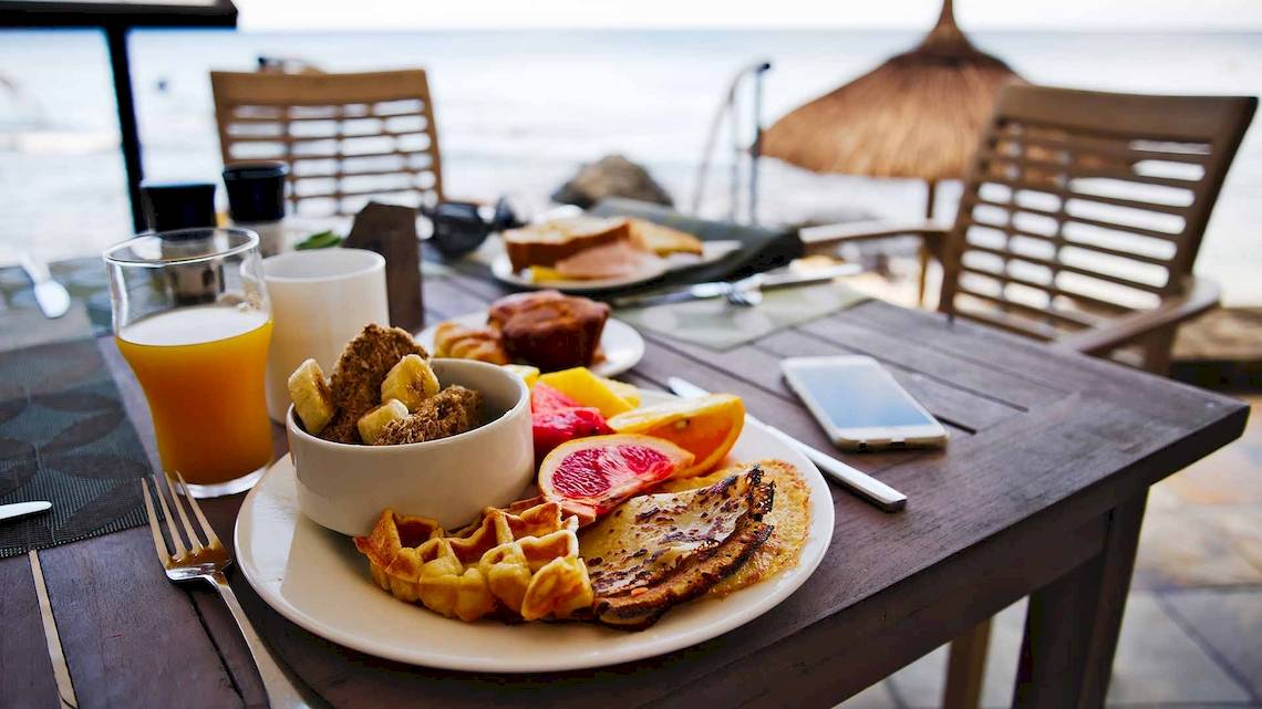 Frühstück am Strand im Recif Attitude Hotel mit Waffeln, Früchten und Getränken.