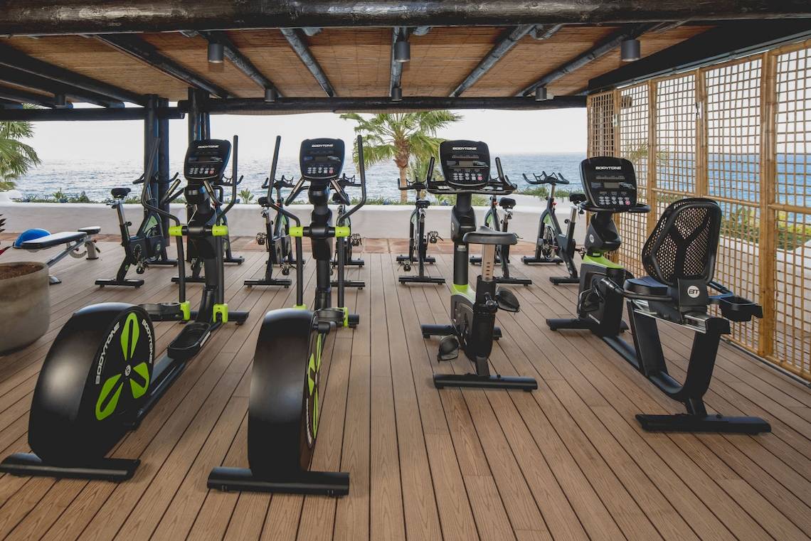 Fitnessraum im Recif Attitude Hotel mit Blick auf das Meer und modernen Trainingsgeräten.