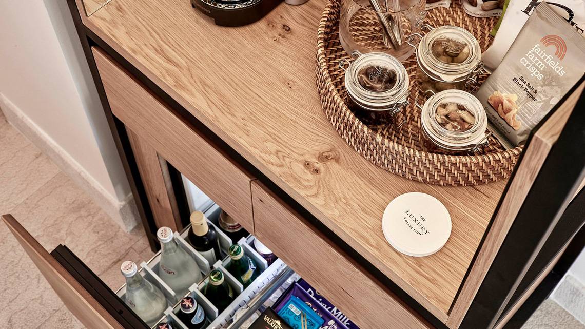 Minibar im Blue Palace Resort & Spa mit Getränken, Snacks und einem weißen Etikett.