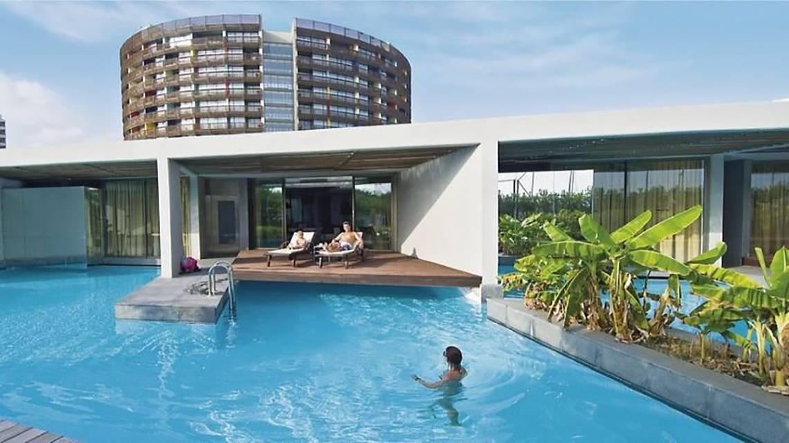 Schwimmbad und Loungebereich im Nirvana Cosmopolitan Hotel mit zwei Personen auf Liegen.
