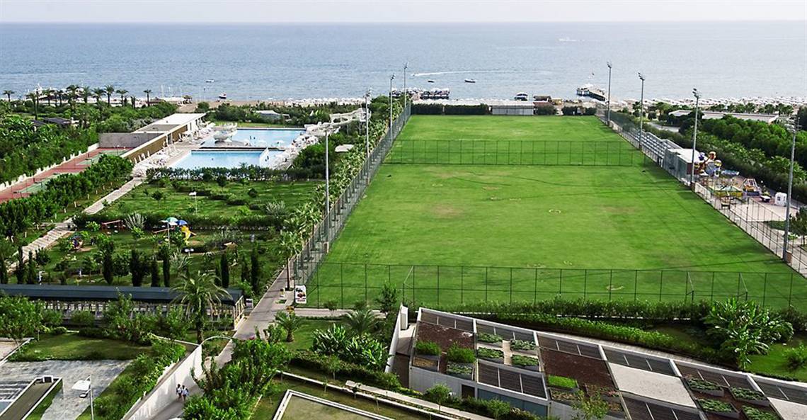 Luftaufnahme des Nirvana Cosmopolitan Hotels mit einem großen Sportplatz und einem Pool im Freien.