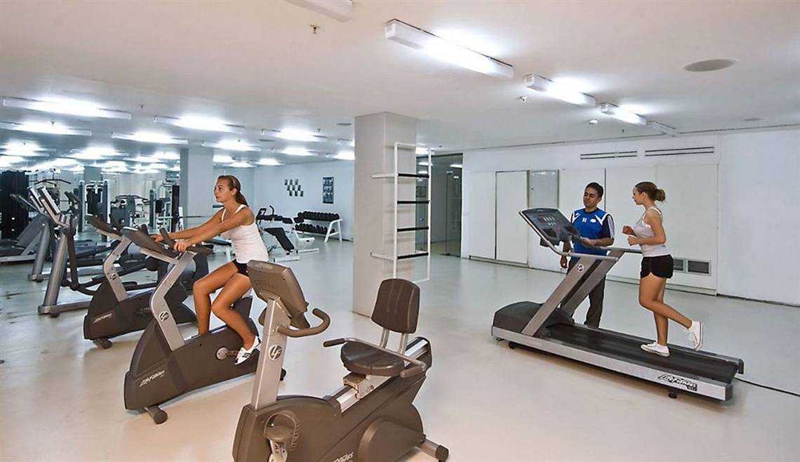 Fitnessstudio im Nirvana Cosmopolitan Hotel mit Frauen auf Geräten und einem Mann, der auf dem Laufband läuft.
