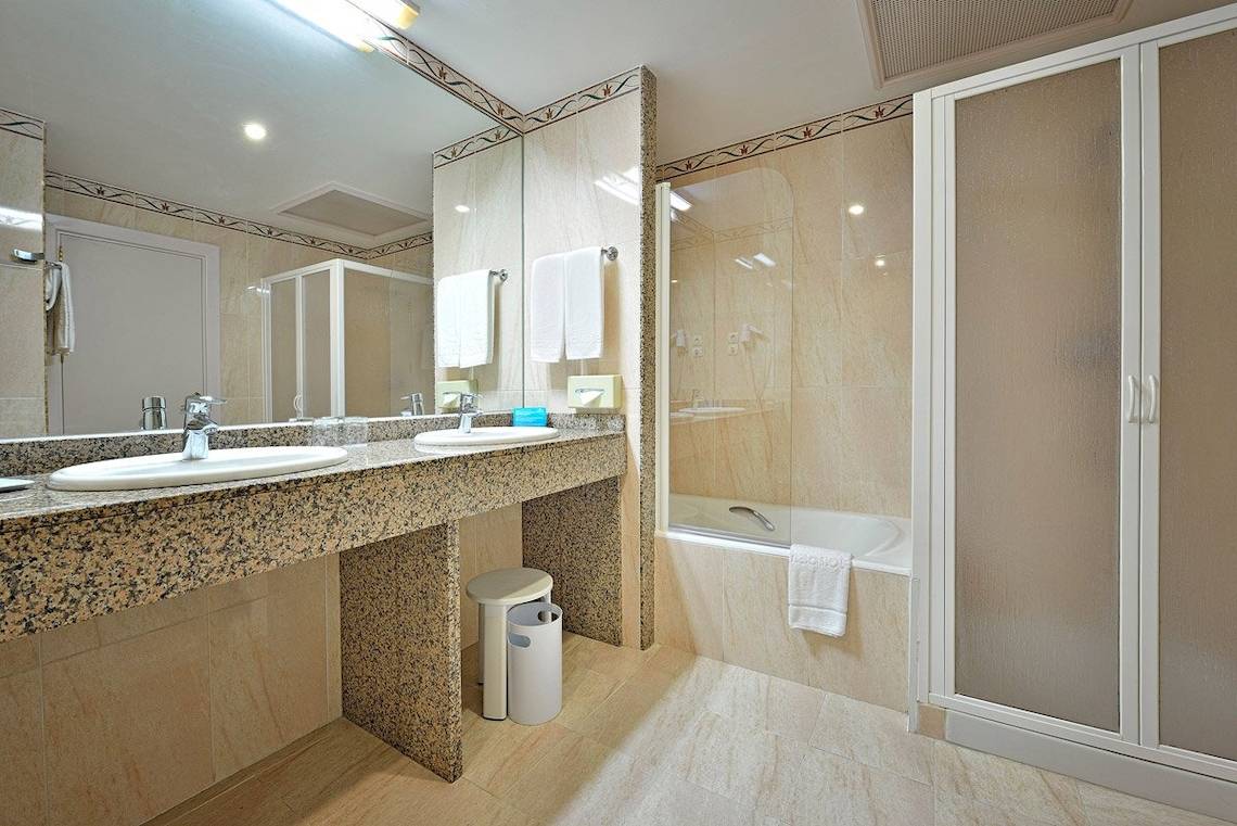 Badezimmer im MAC Puerto Marina Hotel mit zwei Waschbecken, Dusche und Badewanne.