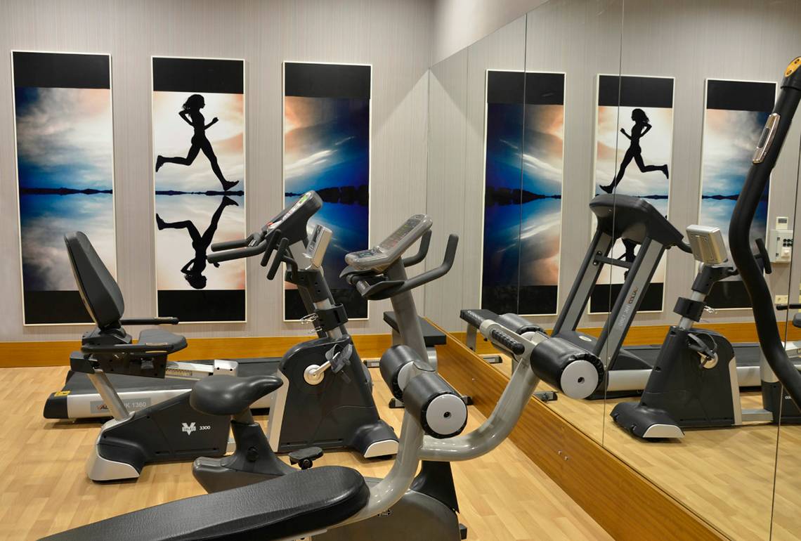 Fitnesscenter im Port Side Resort mit Laufband und Fahrradtrainern hinter großen Spiegeln