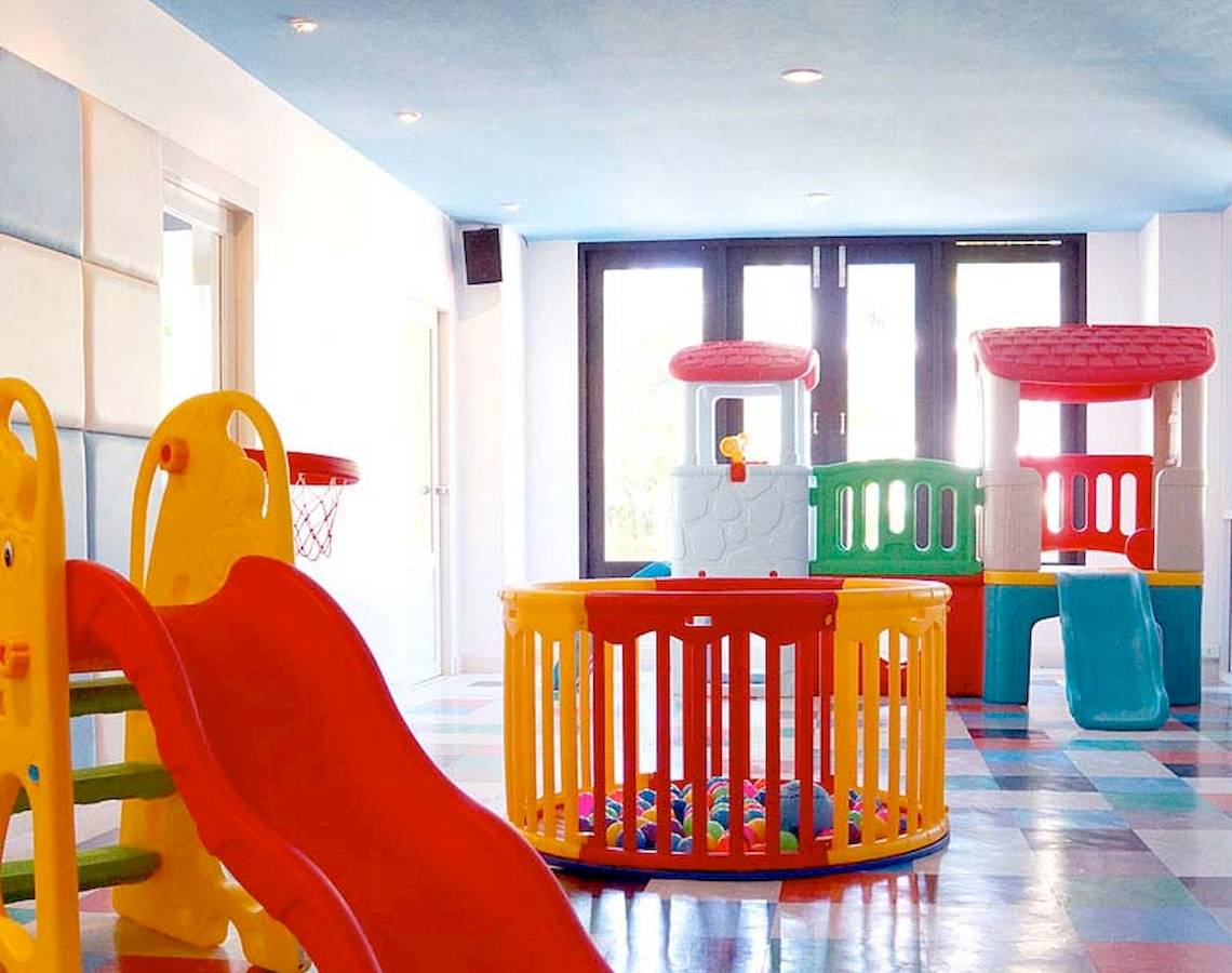 Kinderspielbereich im Apsara Beachfront Resort mit bunten Spielgeräten und einem großen roten Rutsch.