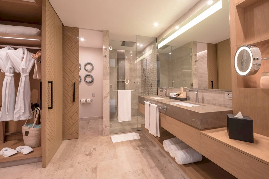 Ein modernes Badezimmer mit einer Glasdusche und einem Doppelwaschbecken, umgeben von Holzmöbeln und weißen Handtüchern.