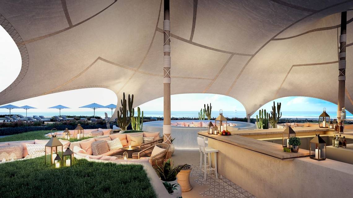 Außenloungebereich des Ikos Andalusia Hotels mit Blick auf das Meer und Kakteen.