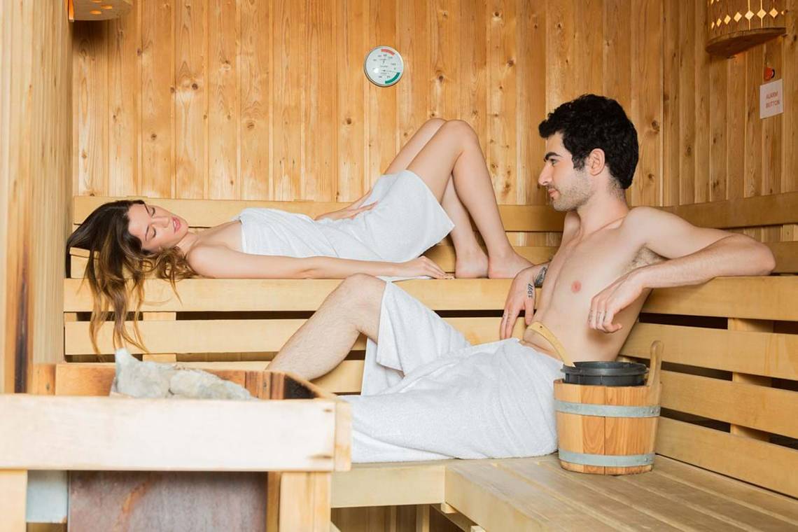 Paar im The Royal Blue Resort in der Sauna mit einem Eimer Wasser