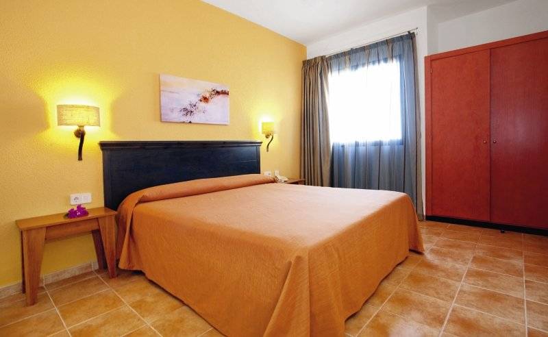 Hotelzimmer im SBH Royal Monica mit gelben Wänden, einem Doppelbett, Nachttischen und einem Schrank.