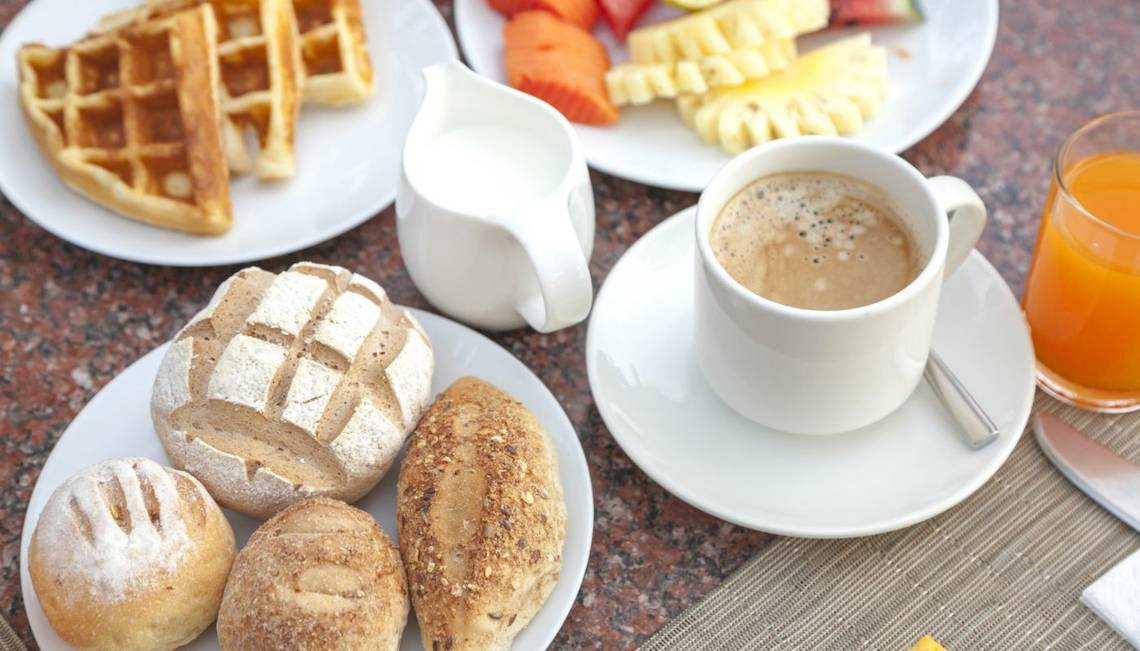 Frühstücksbuffet mit Kaffee, Obst, Waffeln, Brot und Säften auf einem Tisch im Hotel Beyond Resort Khao Lak.