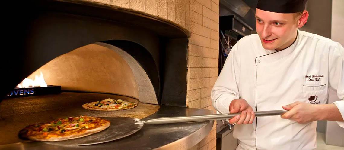 Koch im DoubleTree by Hilton Resort & Spa Marjan Island, der Pizza im Ofen zubereitet.