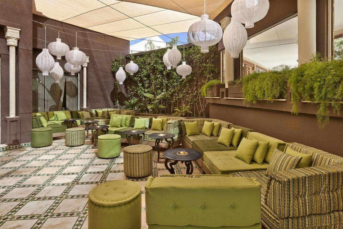 Lounge-Bereich im Palmeraie Palace Hotel mit grünen Sofas, Tischen und dekorativen Lampen.