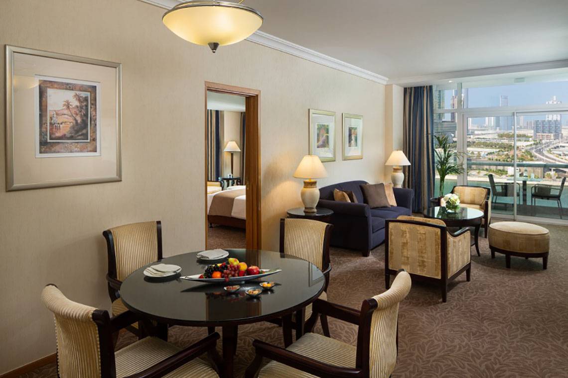 Innenansicht der Suite im Beach Rotana Hotel mit Essbereich und Wohnzimmer.