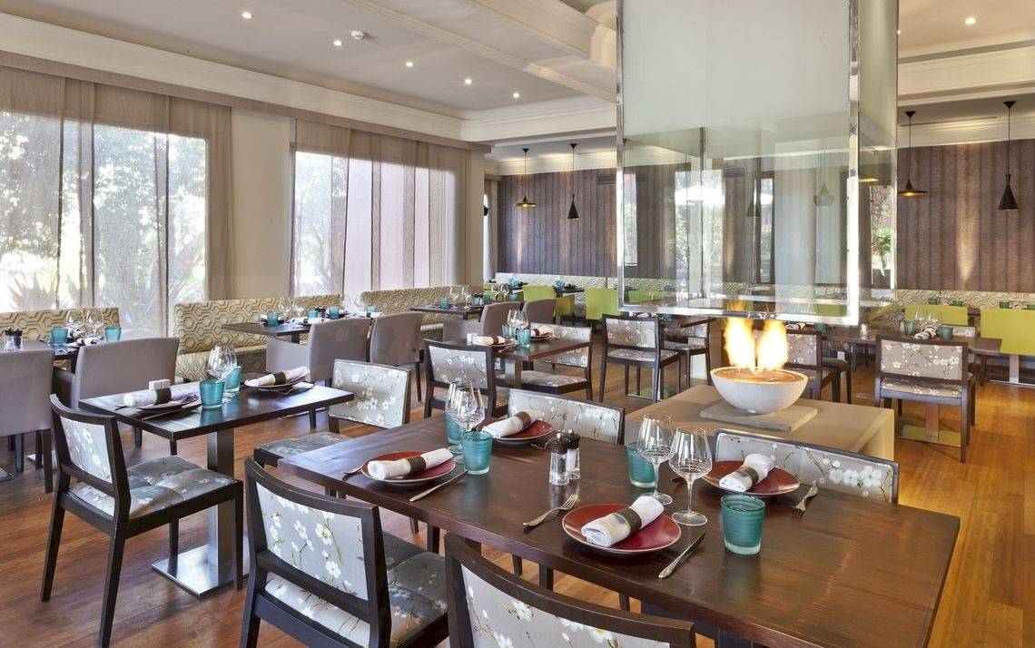 Restaurantbereich im Palmeraie Palace mit gedeckten Tischen, Feuerschüssel und Panoramafenstern.