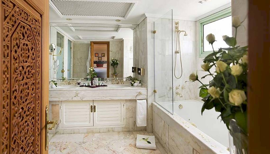 Luxuriöses Badezimmer im Palmeraie Palace Hotel mit Marmorboden, Badewanne, Waschbecken und Regendusche.