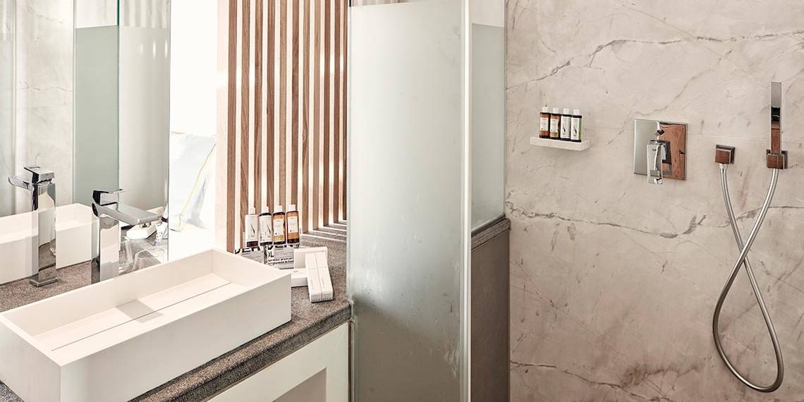 Hotelbadezimmer von Myconian Korali Relais & Chateaux mit modernem Design und Marmorwänden.