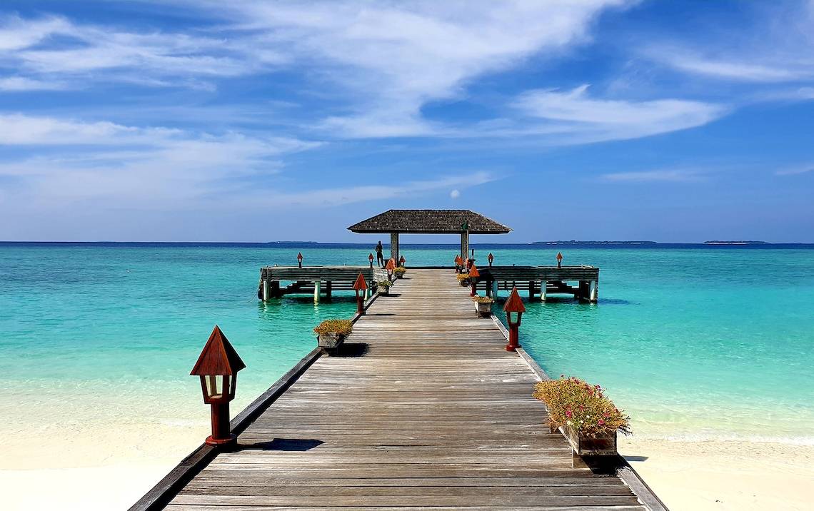 Holzsteg im Meer bei The Barefoot Eco Hotel mit blauem Himmel und Wasser