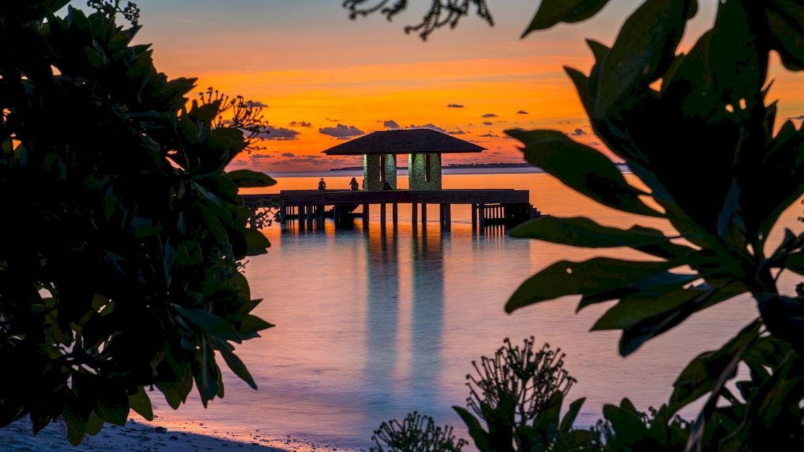 Der Barefoot Eco Hotel bei Sonnenuntergang mit zwei Personen auf der Veranda.