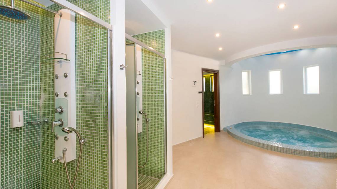 Ein Badezimmer im Iberostar Creta Panorama & Mare mit grünen Fliesen, einer Regendusche und einer Badewanne.